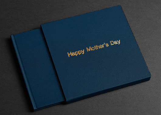 Blue photo book in matching slipcase with `Happy Mother's Day` embossed in gold on the front.